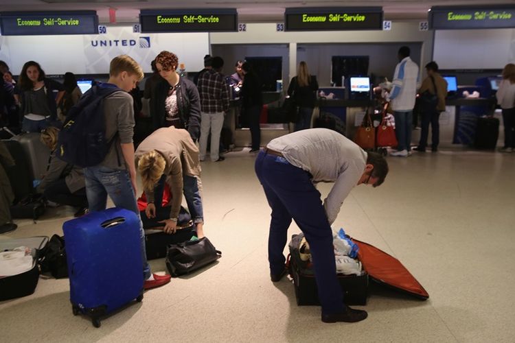 Penumpang mengemasi barang bawaan mereka sebelum melewati mesin pemeriksaan di bandara internasional Newark Liberty.