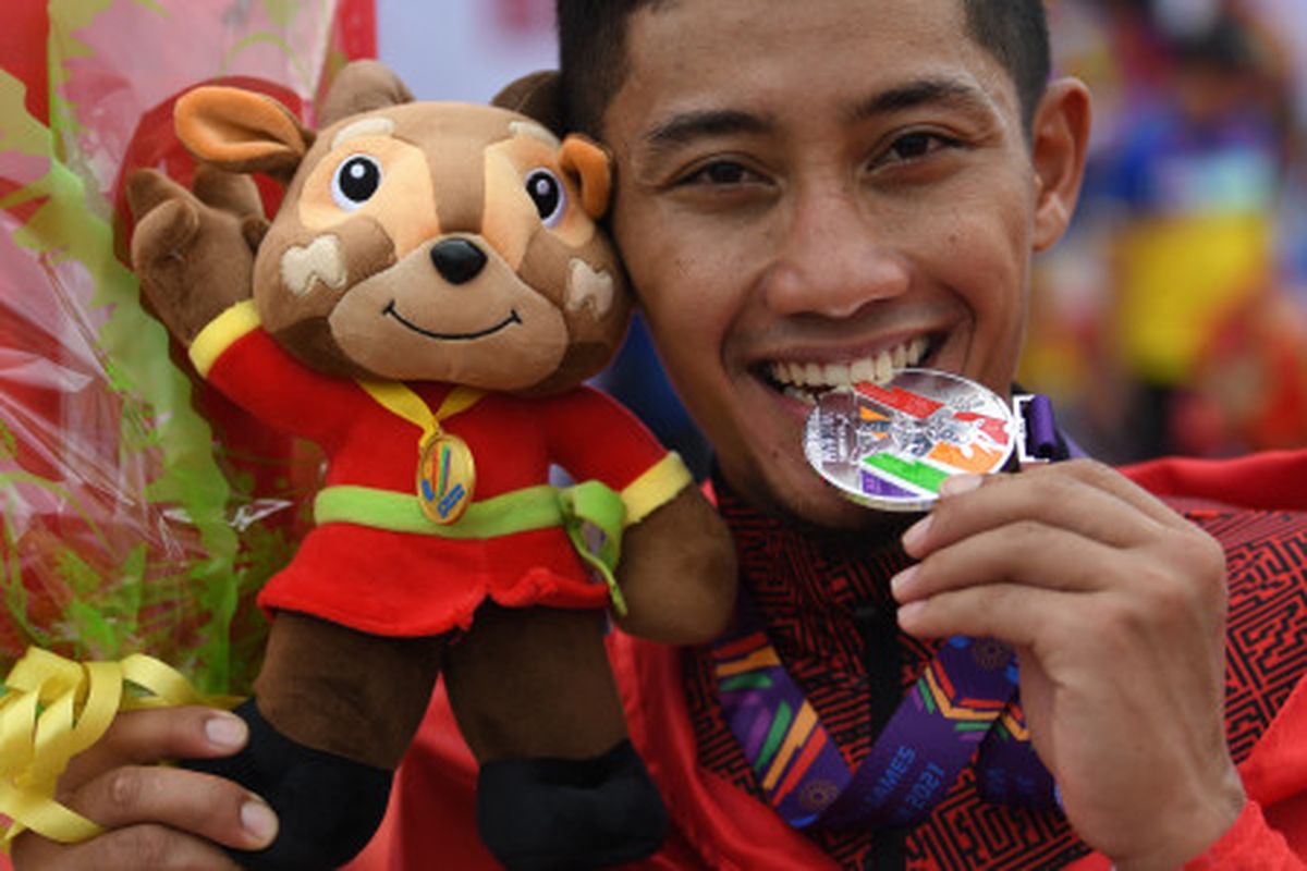Pesepeda Aiman Cahyadi menggigit medalinya usai pengalungan medali nomor individual time trial road cycling putra SEA Games Vietnam 2021 di Hoa Binh, Vietnam, Jumat (20/5/2022). Aiman meraih medali perak dalam perlombaan tersebut dengan catatan waktu 48 menit 37,903 detik