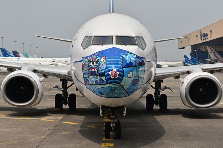 Pesawat Garuda Indonesia Boeing 373-800 NG dengan desain masker di bagian depan pesawat, saat diparkir di lapangan udara di Tangerang, Banten, Senin (12/10/2020). Pemasangan ''masker'' di pesawat tersebut digelar untuk mendukung kampanye Gerakan 'Ayo Pakai Masker' dalam rangka penanggulangan pandemi Covid-19.