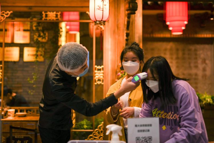 Potret penyesuaian di sebuah restoran di Chengdu, China yang membuka kembali gerainya. Tampak pengunjung ditembakkan pengukur suhu.