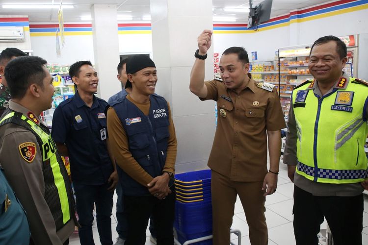 Wali Kota Surabaya Eri Cahyadi (kedua dari kanan) bersama anggota kepolisian, pegawai minimarket, serta seorang juru parkir saat melakukan sosialisasi di lapangan terkait penerapan parkir digital.
