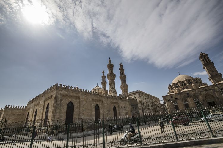 Beberapa orang berjalan di sekitar masjid Al-Azhar  di ibu kota Mesir, Kairo yang ditutup pada 20 Maret 2020, setelah otoritas agama Muslim di negara itu memutuskan untuk meniadakan sementara sholat Jumat, untuk menghindari pertemuan dan penyebaran penyakit Covid-19.