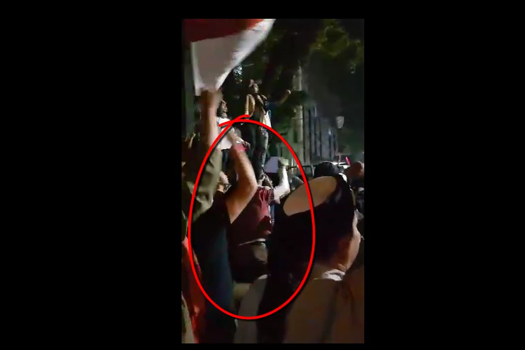 seorang pria berkaos merah dan lengan panjang putih tampak melempar sesuatu ke arah polisi dalam aksi unjuk rasa di depan gedung DPRD Sumut, Jumat (24/5/2019) yang lalu. 