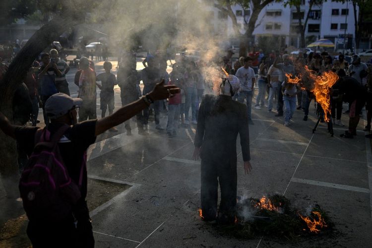 Sebuah boneka yang mewakili Perdana Menteri Israel Benjamin Netanyahu (kanan) dibakar selama ritual tradisional ?Pembakaran Yudas?, yang diadakan dalam rangka perayaan Pekan Suci, di lingkungan San Agustin di Caracas, pada 9 April 2023. 