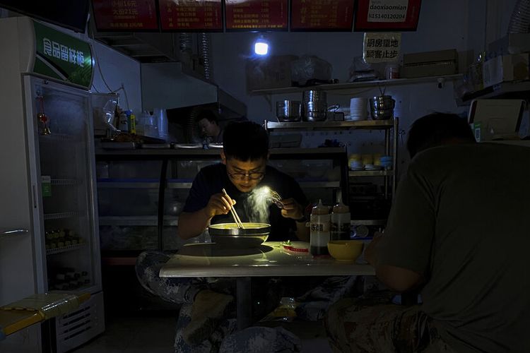 Akibat krisis energi China yang berdampak pada pemadaman listrik, seorang pria di Shenyang, provinsi Liaoning, China timur laut, pada Rabu (29/9/2021) menggunakan senter ponselnya untuk menerangi semangkuk mi ketika sarapan di restoran.