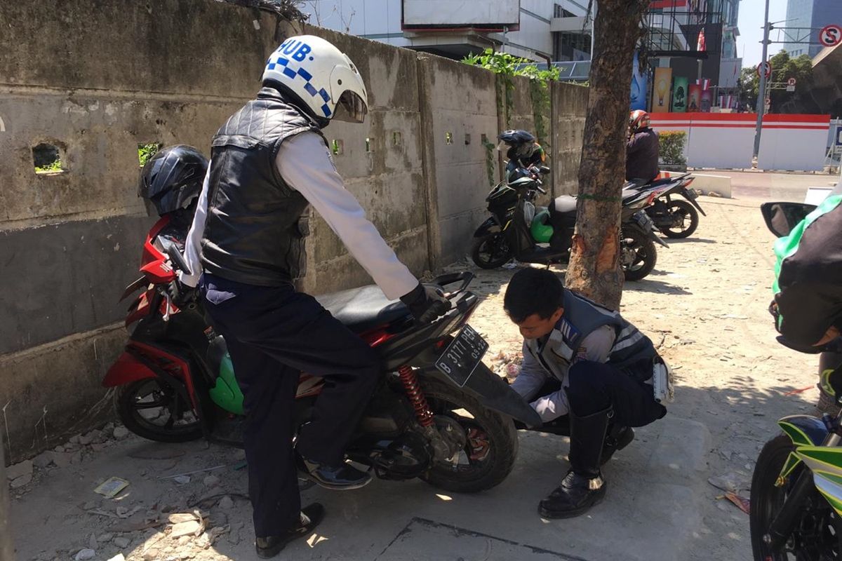 Petugas Dishub gembosi ban motor yang parkir liar di kawasan Setiabudi, Jakarta Selatan, Rabu (21/8/2019)