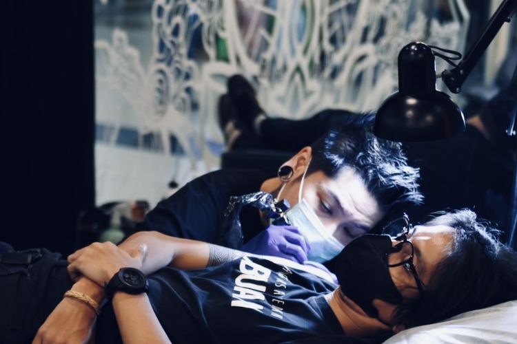 Arnaz Aditya Pratama tattoo artist sekaligus pemilik Sankara Tattoo Skinart studio saat menato kliennya di Pakuwon Trade Center (PTC) Surabaya.

