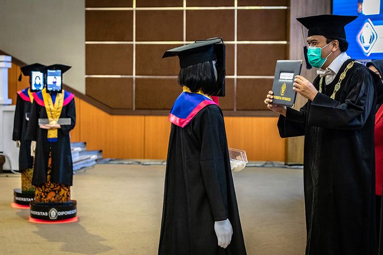 Rektor UNDIP Yos Johan Utama (kanan) menyerahkan ijazah kelulusan kepada robot peraga saat wisuda secara daring di Universitas Diponegoro (UNDIP), Semarang, Jawa Tengah, Senin (27/7/2020). WIsuda ke-159 UNDIP yang diikuti 2.561 lulusan itu menggunakan teknologi robot peraga yang menggantikan kehadiran fisik para wisudawan maupun wisudawati karena sejumlah kebijakan protokol kesehatan dalam upaya mencegah penyebaran COVID-19.