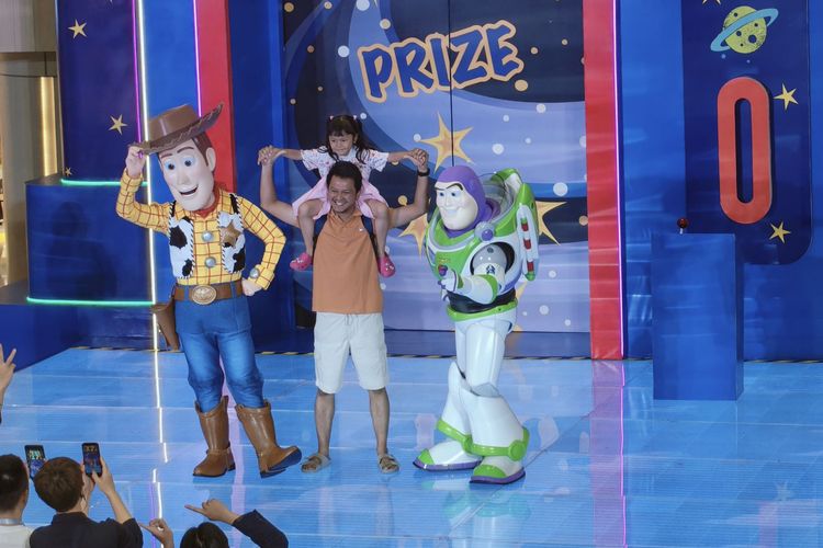 Seorang pengunjung bersama anaknya foto bersama dua karakter dalam film Toy Story, Woody dan Buzz Lightyear dalam meet and greet yang digelar di Tunjungan Plaza 3 Surabaya, Kamis (18/12/2025) malam.