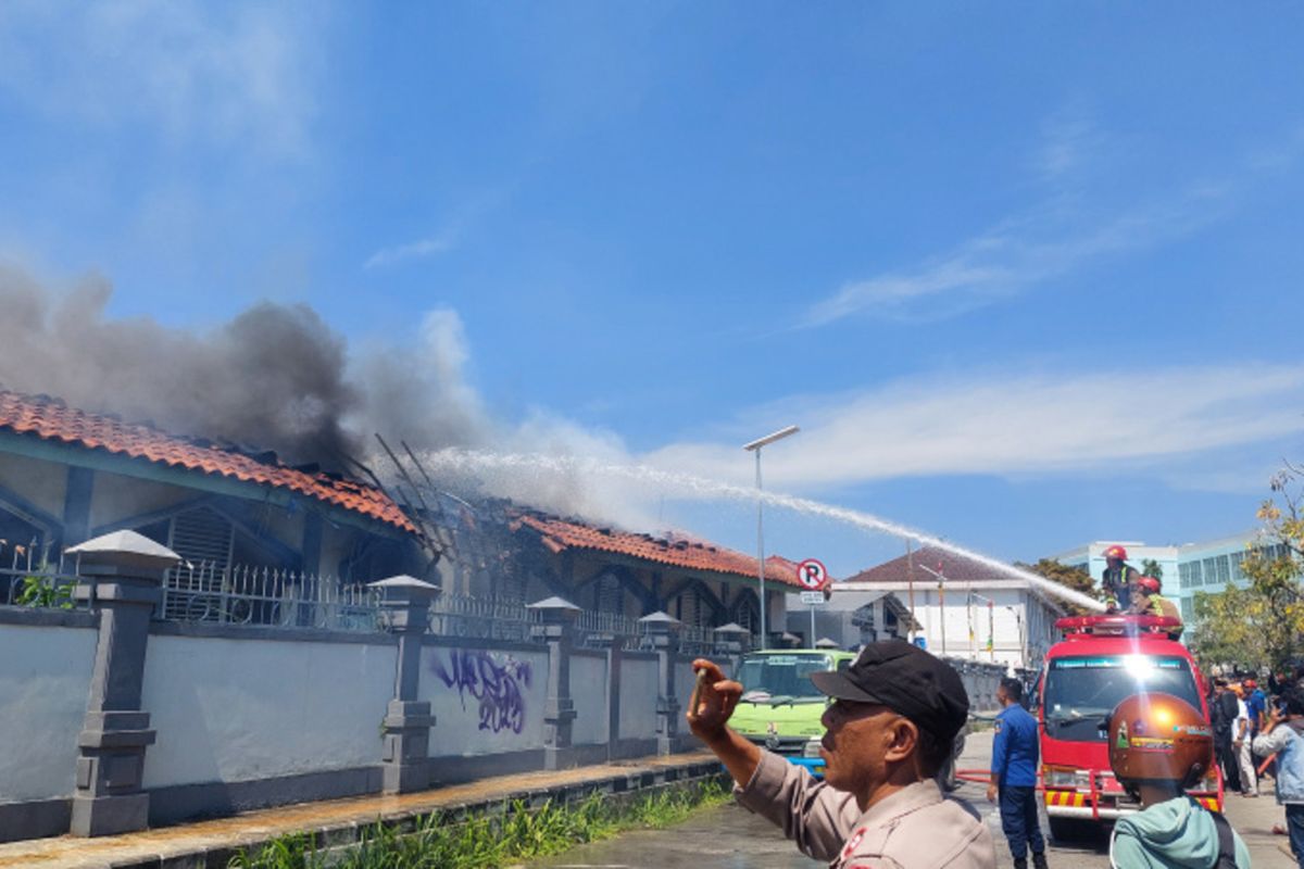 Petugas pemadam kebakaran mencoba melakukan pemadaman dengan disaksikan warga