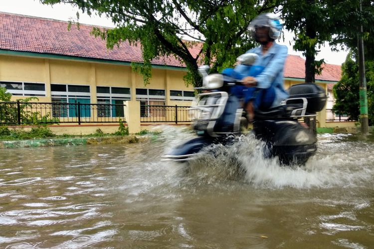 Seorang pengendara motor Vespa menerobos genangan air di kelurahan Jungcangcang Pamekasan, Jumat (1/2/2019). 