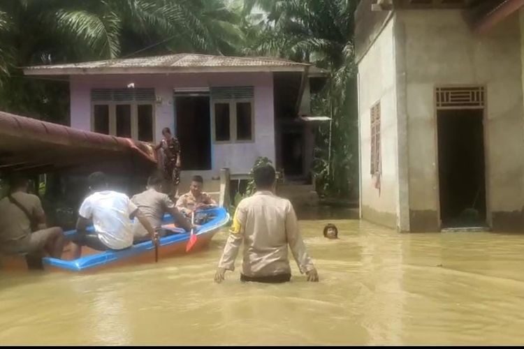 Petugas Polsek Peranap saat menerjang banjir menuju rumah-rumah warga untuk menyalurkan bantuan, di Desa Setako Raya, Kecamatan Peranap, Kabupaten Indragiri Hulu, Riau, Senin (18/12/2023).