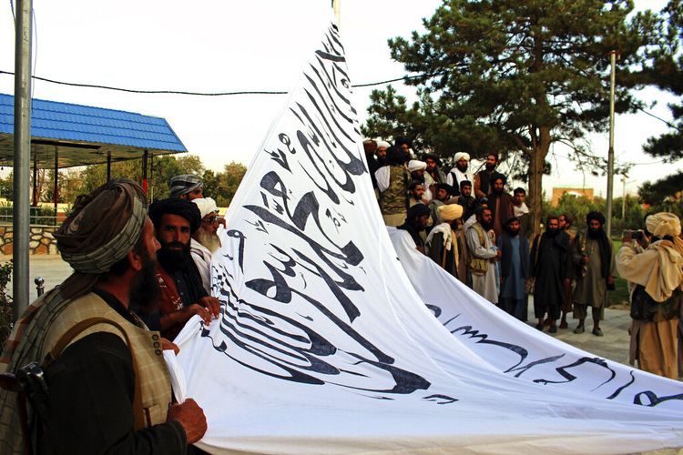 Para milisi Taliban mengibarkan bendera mereka di rumah gubernur provinsi Ghazni, Ghazni, Afghanistan, Minggu (15/8/2021).