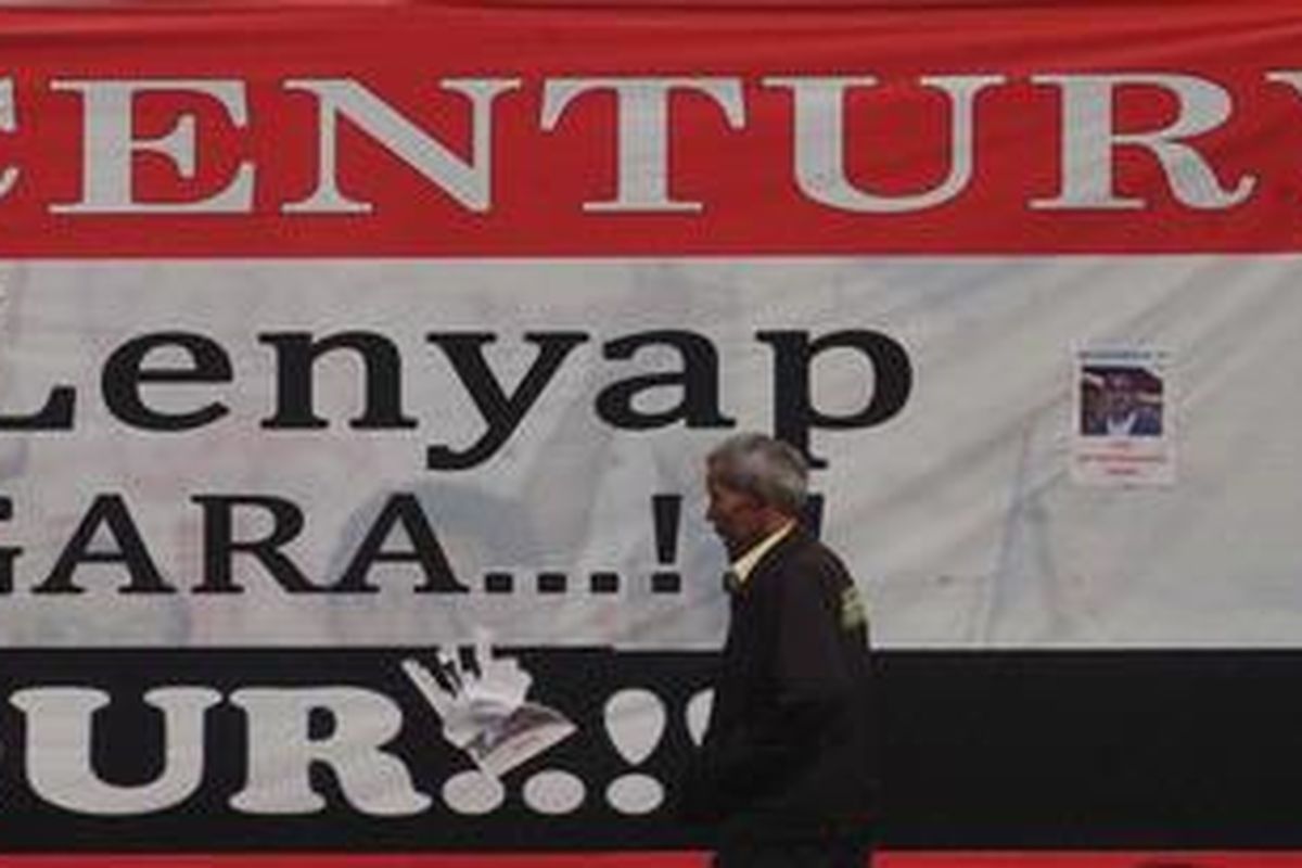 Warga melintas di samping tulisan kritikan terhadap penuntasan kasus skandal bank century di Jalan Diponegoro, Jakarta, Minggu (17/7/2011). Penyelesaian kasus skandal Bank Century yang diduga telah merugikan negara sebesar Rp 6,7 triliun tersebut hingga kini masih belum tuntas. 