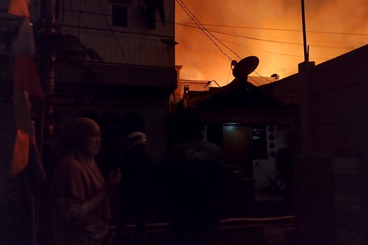 Seorang warga, Ami (40),  menangis sambil menelepon anaknya karena pulang dengan keadaan rumah sudah terbakar hangus, Gang Ober, Gambir, Jakarta Pusat, Rabu (23/8/2023). (KOMPAS.com/XENA OLIVIA)