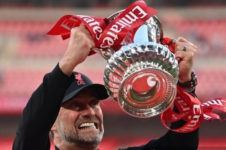 Pelatih Liverpool Juergen Klopp mengangkat trofi Piala FA setelah pertandingan final melawan Chelsea di Stadion Wembley, London, Inggris Sabtu (14/5/2022). 