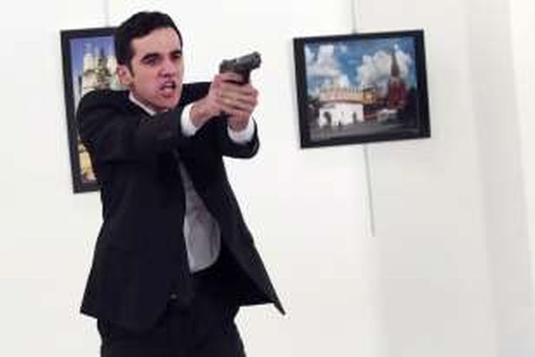 Seorang pria bernama Mevlut Mert Altintas, menodongkan pistolsetelah menembak Duta Besar Rusia untuk Turki Andrei Karlov, saat pembukaan pameran foto di Gedung Cagdas Senat Merkezi, Ankara, Senin (19/12/2016).