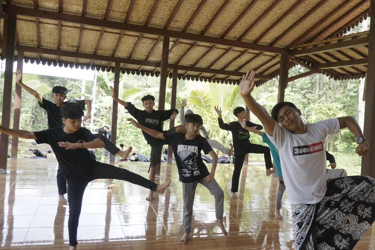 
Irfan Efendi (17), salah satu anak Kampung Batara terlihat melatih teman-temannya untuk menari di sebuah bangunan berdinding bambu di Kampung Papring, Kelurahan Kalipuro pada Minggu (13/8/2023).
