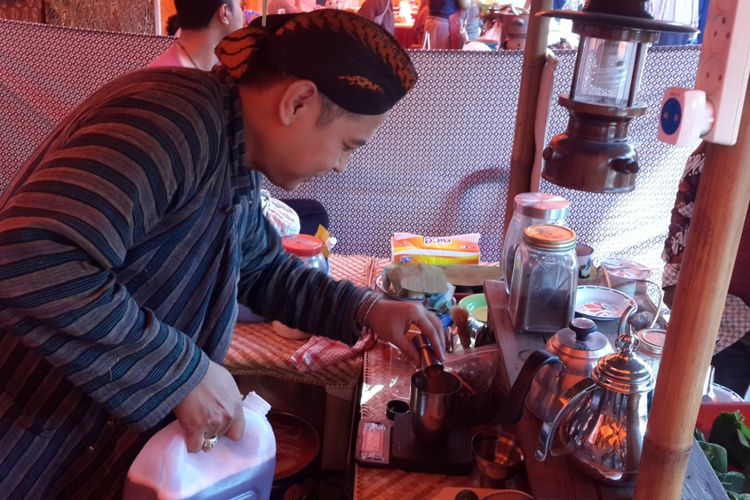 Arief Puji Prasetyo, salah satu penjual bir jawa saat menyajikan bir jawa kepada pelanggannya di Festival Lawang Kota Tua, Kamis (27/9/2018)