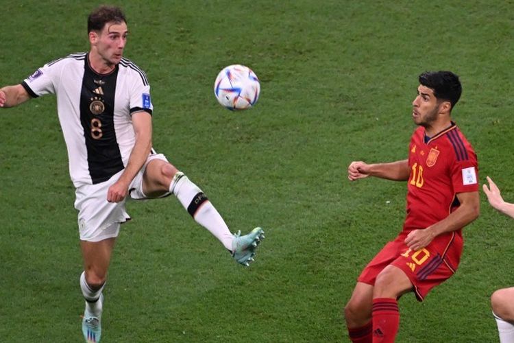 Leon Goretzka (8) berduel dengan Marco Asensio (10) dalam laga Grup E Piala Dunia 2022 antara Spanyol vs Jerman di Stadion Al Bayt, Al Khor, Qatar, 27 November 2022. Spanyol masih memimpin klasemen Piala Dunia 2022 Grup E usai bermain imbang 1-1 dalam laga ini. Sementara itu, Jerman juga masih memiliki peluang lolos ke 16 besar. (Photo by Kirill KUDRYAVTSEV / AFP)