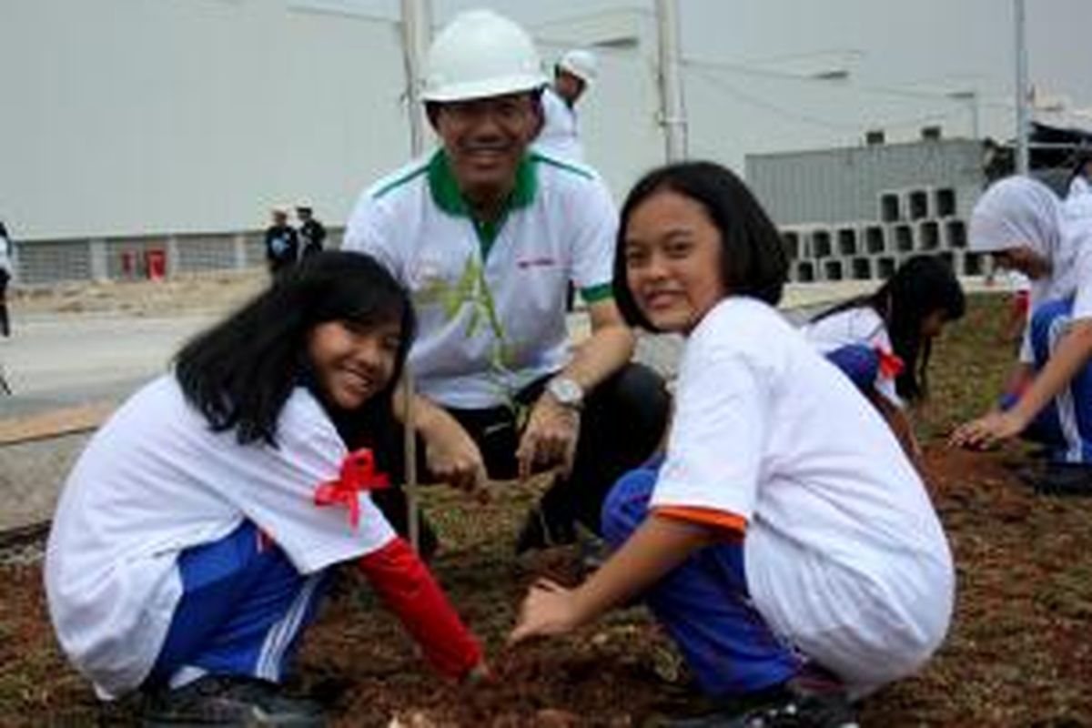 Masanobu Fujii, Vice President PT Sharp Electronics Indonesia, melakukan penanaman pohon bersama siswi-siswi sekolah dasar.