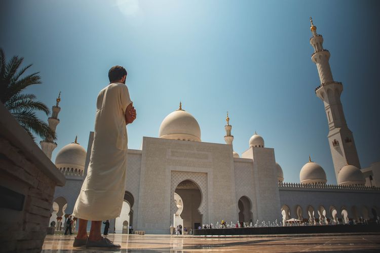 Seorang pria berdiri di depan Masjid Agung Sheikh Zayed, Abu Dhabi.