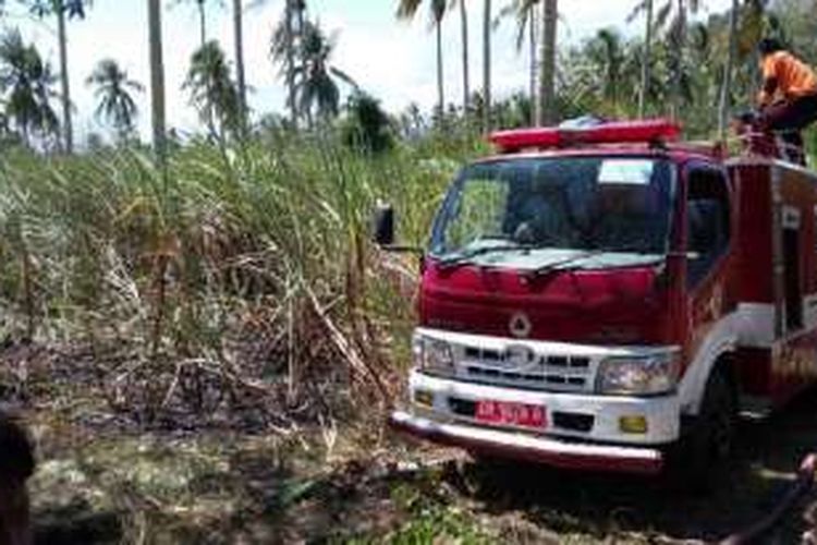Mobil pemadam kebakaran berupaya memadamkan api di lahan tebu di kabupaten Gorontalo. Kebun ini merupakan kerjasama antara warga desa dengan pabrik gula Rajawali