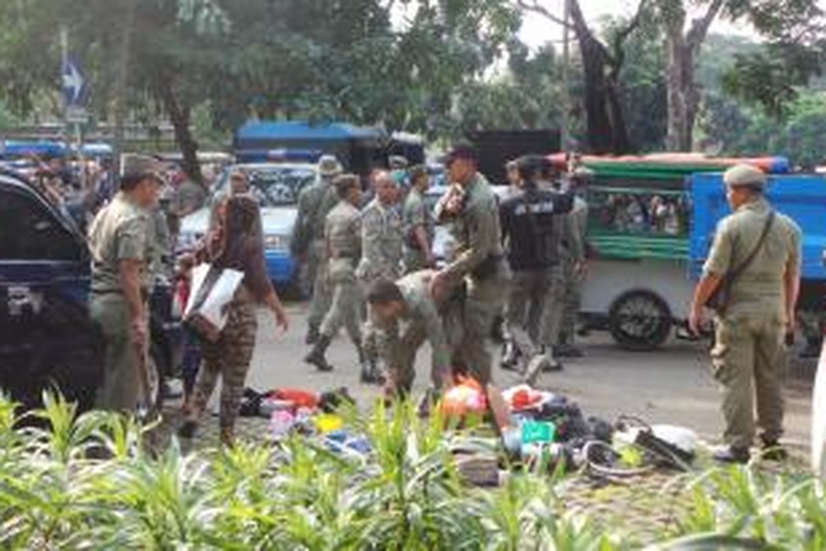 Petugas satuan polisi pamong praja DKI Jakarta menertibkan pedagang kaki lima di dalam kompleks Monumen Nasional, Jakarta Pusat. Selasa (16/6/2015).