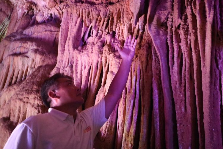 Seorang wisatawan memegang stalaktit yang ada di Goa Gong, Pacitan, Jawa Timur, Rabu (29/1/2020).