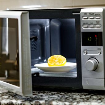 Ilustrasi membersihkan microwave dengan lemon. 