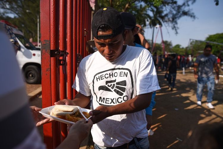Migran asal Amerika Tengah yang mengikuti rombongan konvoi menerima pembagian sarapan di kamp di perbatasan Meksiko, Rabu (4/4/2018).