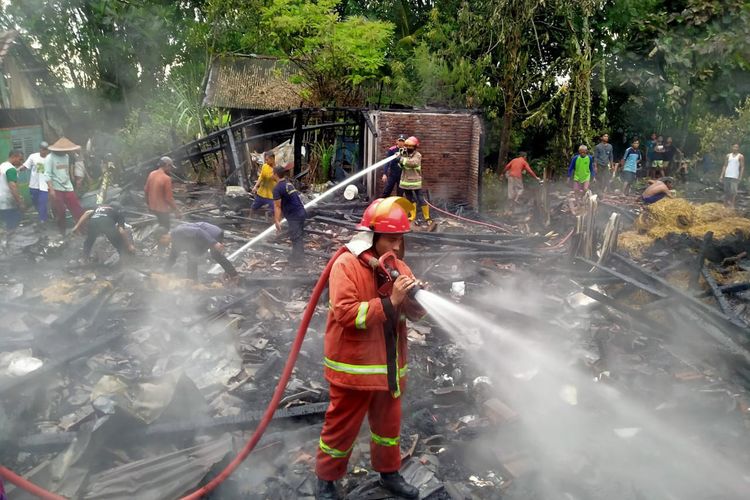 Petugas saat berusaha memadamkan api yang membakar tiga rumah dan kandang, serta menghanguskan satu ekor sapi di Desa Kuwurejo, Kecamatan Bluluk, Lamongan, Jawa Timur, Sabtu (7/1/2023).