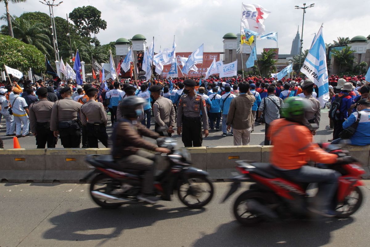 Pengguna jalan melintasi jalur Transjakarta saat terjadi demonstrasi dari elemen buruh  depan Gedung DPR/MPR RI, Jakarta, Selasa (6/9/2022). Mereka menolak kenaikan harga BBM.