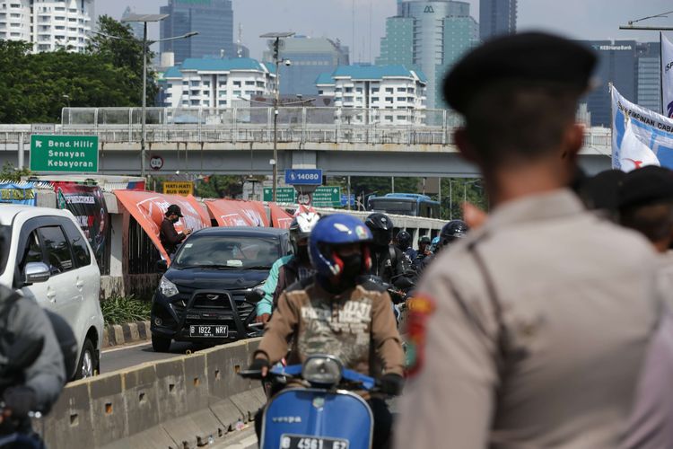 Pengguna jalan melintasi jalur Transjakarta saat terjadi demonstrasi dari elemen buruh  depan Gedung DPR/MPR RI, Jakarta, Selasa (6/9/2022). Mereka menolak kenaikan harga BBM.