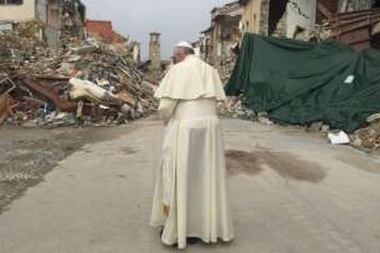 Gambar lain memperlihatkan Paus berdiri sendiri dan berdoa menghadap tumpukan batu dari reruntuhan gedung yang masih tersisa di sana. 