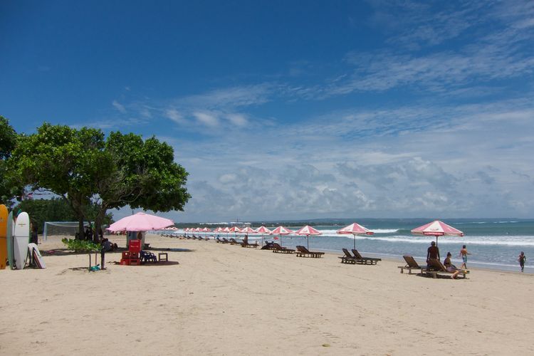 Ilustrasi pengunjung menikmati suasana pantai di Pantai Berawa, Badung, Bali.