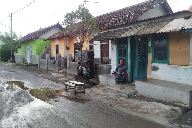 Satinah berada di depan rumahnya sembari mempersiapkan diri jika banjir tiba-tiba melanda. 