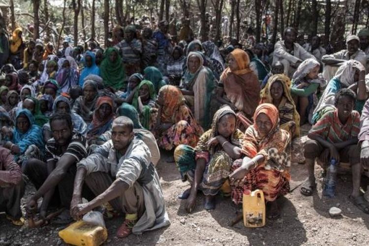 Anggota masyarakat Chelko, Ethiopia, menunggu untuk menerima jatah persediaan makanan, seperti gandum, minyak, dan kacang polong.  Kekeringan telah menyebabkan mereka kekurangan pangan, dan terpaksa harus dijatah secara bergilir untuk mendapat bantuan.
