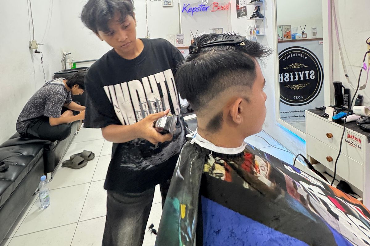 Mesa, siswi SMK Canda Bhirawa Pare, Kabupaten Kediri, Jawa Timur, saat mencukur rambut kliennya di Stylish Barbershop Pare, Sabtu (22/2/2025).