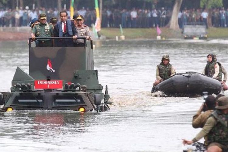 Presiden Joko Widodo, didampingi Panglima TNI Jenderal Gatot Nurmantyo (kiri) dan Kepala Polri Jenderal (Pol) Tito Karnavian (kanan), menaiki panser amfibi, Anoa Amphibious produksi PT Pindad, saat menyeberangi danau di kompleks Markas Besar TNI, Cilangkap, Jakarta, Senin (16/1). Uji coba panser amfibi ini berlangsung saat Presiden hadir dalam acara Rapat Pimpinan TNI  2017