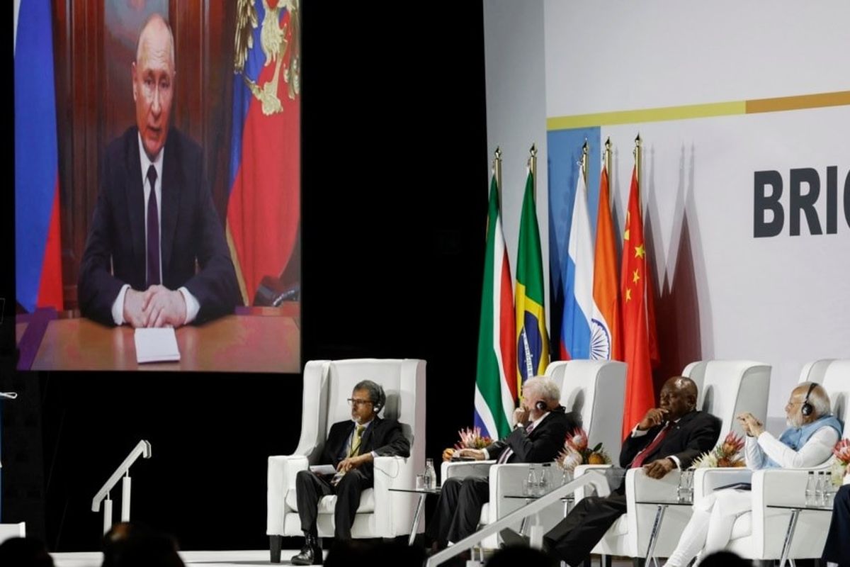 Presiden Rusia Vladimir Putin (tampak di layar monitor) memberikan pidato di KTT BRICS melalui rekaman video, Selasa (22/8/2023).