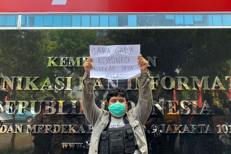 Sandya salah satu pengguna PayPal membentangkan sebuah tulisan protes akibat diblokirnya sejumlah platform digital oleh Kemenkominfo di depan Kantor Kementerian Komunikasi dan Informatika, Jakarta Pusat, Senin (1/8/2022).