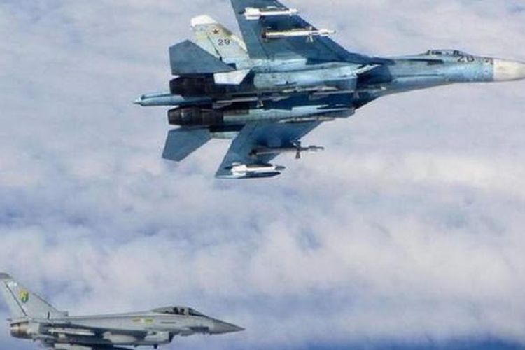 Sebuah pesawat tempur Sukhoi Su-27 (atas) milik Rusia diawasi sebuah pesawat tempur Royal Air Force (RAF) Typhoon Inggris (bawah) saat sejumlah pesawat militer Rusia terbang di wilayah udara internasional dekat negara-negara Baltik, Senin (16/6/2014)
