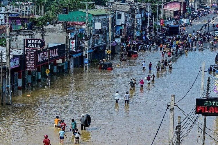Warga korban banjir Sri Lanka berjalan menerjang genangan air di pinggiran Ibu Kota Colombo, 30 November 2025. Banjir dan tanah longsor kali ini menewaskan sedikitnya 334 orang, terparah sejak 2023. Sri Lanka Tetapkan Keadaan Darurat usai Banjir Tewaskan 330 Korban Lebih