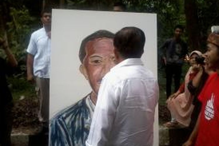 Cawapres Jusuf Kalla saat menambahkan goresan di lukisan wajah Jokowi di Taman Babakan Siliwangi Bandung, Sabtu (21/6/2014).