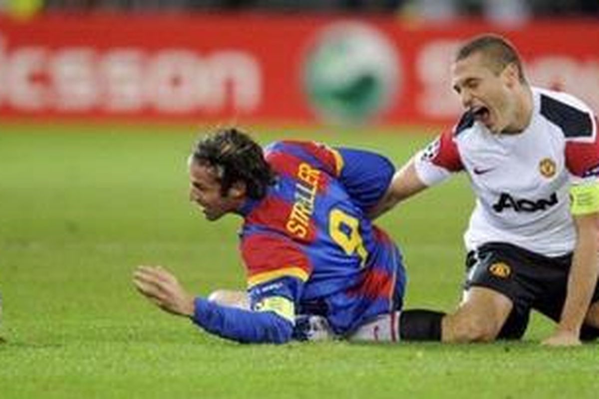 Bek Manchester United, Nemanja Vidic (putih-hitam), mengerang kesakitan saat kaki kanannya tertimpa badan striker Basel, Marco Streller (merah-biru), ketika kedua tim berhadapan di laga terakhir penyisihan Grup C Liga Champions, Rabu atau Kamis (8/12/2011) dini hari WIB.