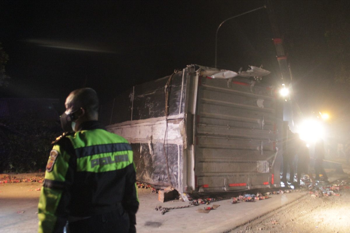 Seorang anggota polisi sedang mengawal proses evakuasi badan truk tronton yang terguling dan menutup badan jalan di jalur Gekbrong, Cianjur, Selasa (28/9/2021). Truk terlibat tabrakan dengan enam kendaraan dan menyebabkan dua orang tewas.