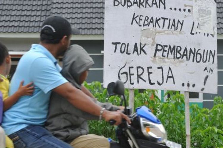 Penduduk di Bekasi melewati tulisan tolak pembangunan gereja di dekat GPIB Filadelfia, Bekasi, yang disegel pada 25 Desember 2012. 