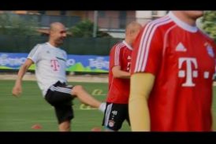 Pelatih Bayern Muenchen, Pep Guardiola (kiri) terlihat tengah bercanda sambil menendang bokong Arjen Robben. 