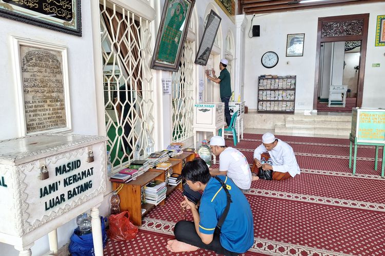 Momen peziarah membacakan Surat Yasin di depan makam keramat Masjid Luar Batang. Selasa (19/3/2024).
